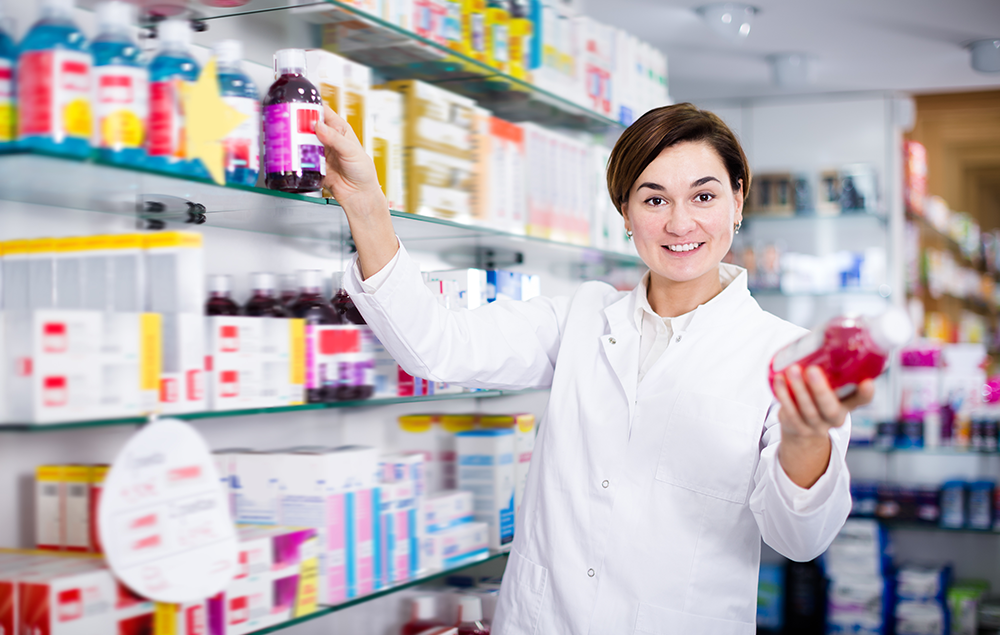 Pharmacy worker holding up two similar medicines.